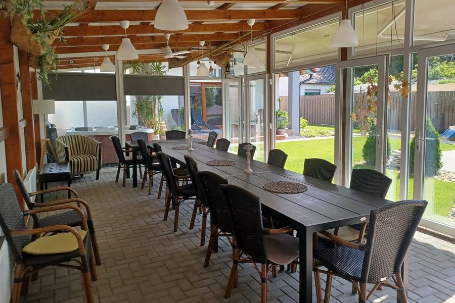 A Siófoki Apartmanok fedett közösségi tere hosszú étkezőasztallal és jakuzzival